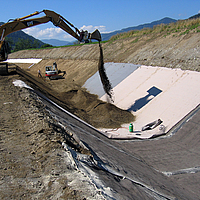 Covering the water channel by installing concrete mats and subsequent sand filling with the help of an excavator.