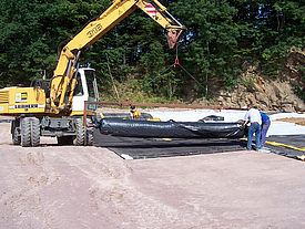 With the help of a crane, the geosynthetics are unrolled from the rolls and installed to cover the landfill body