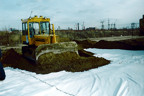 Soil is spread over the laid Stabilenka using a caterpillar tractor