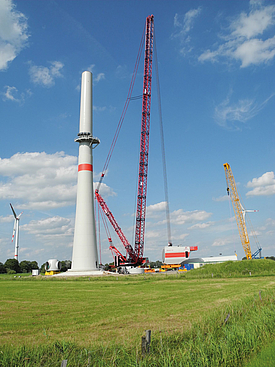 A crane lifts the nacelle onto the wind turbine