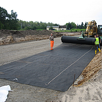 Men roll out geofabric for sinkhole bridging
