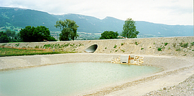 Rainwater retention basin sealed with concrete mats and riprap revetment and filled with water