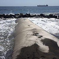 Built-in geotextile breakwater in the sea in the background, water blocks against which the waves crash