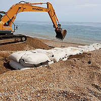Installation of SoilTain Bags on a gravel beach with dredger for flood protection