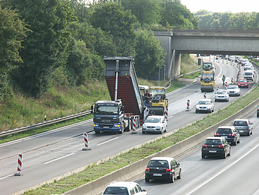 A close-up of a lorry laying new tarmac on a road.