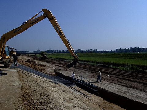 Laying the clay sealing membrane using an excavator.