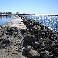 Dam made of geosynthetics, covered with stones and sand