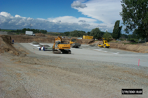 An excavator lays the Stabilenka and a wheel loader spreads gravel