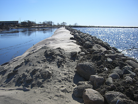 Covering of installed tubes with armourstones